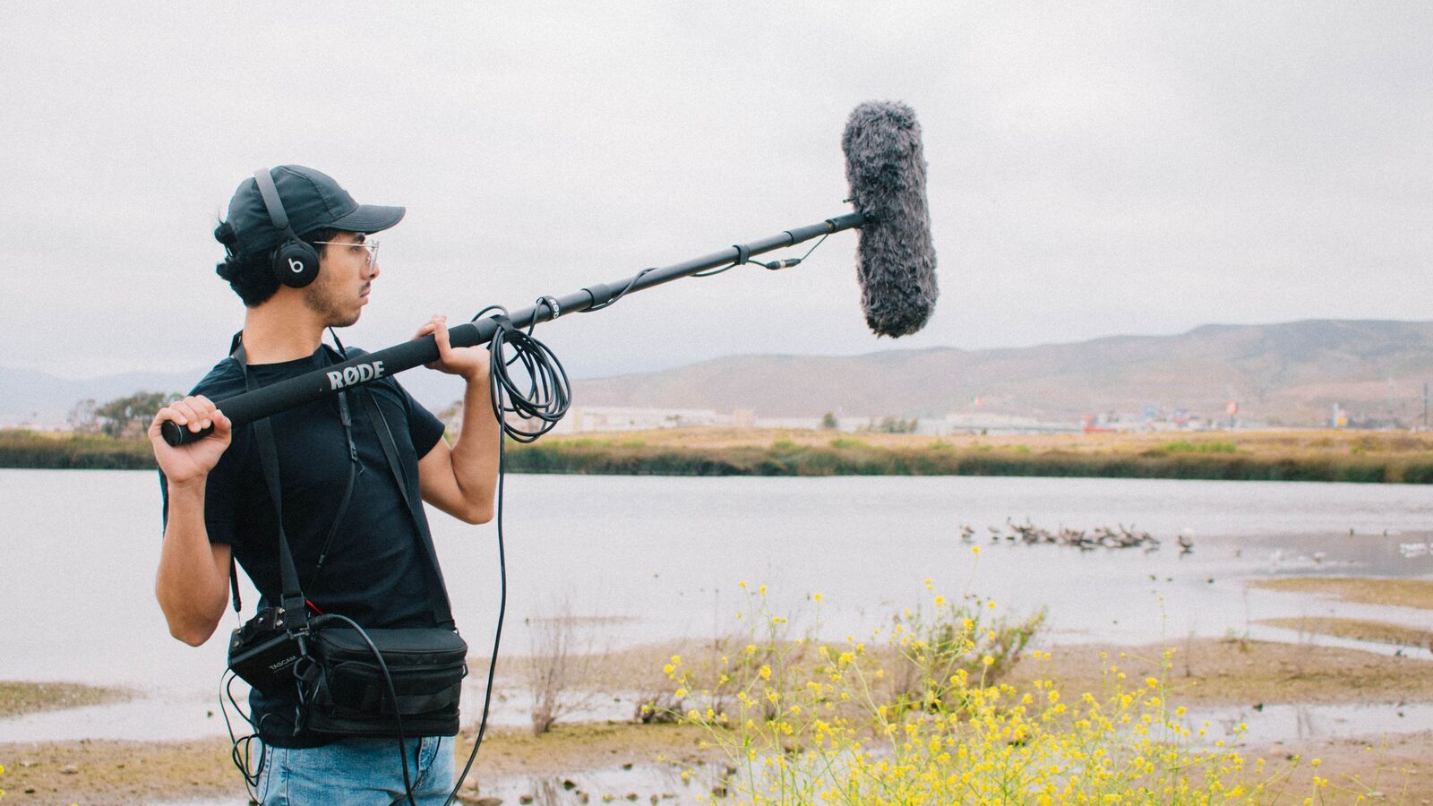 Sound recordist capturing ambient sound outdoors with a boom microphone