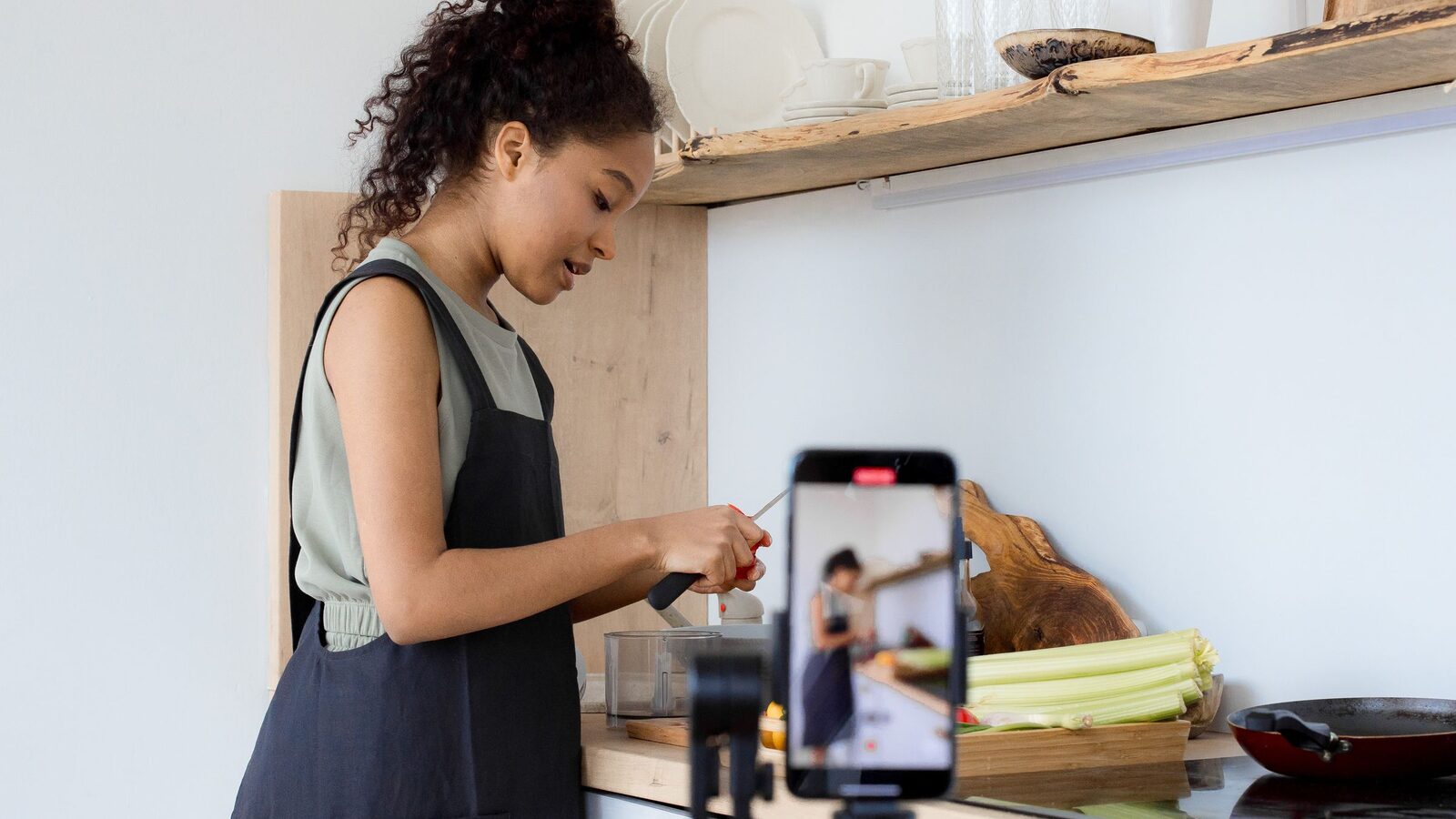 Woman filming herself cooking with a smartphone on a stand