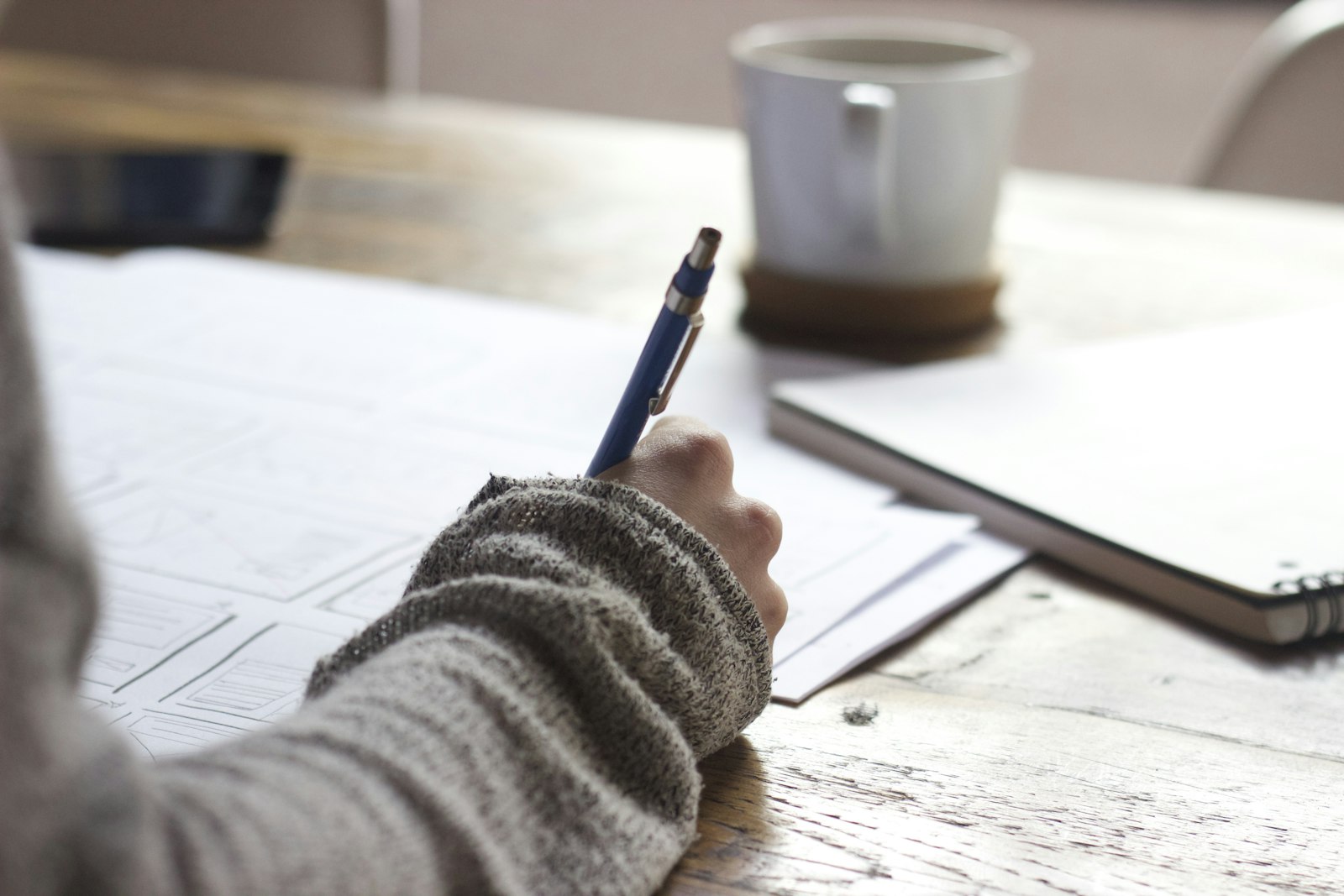 Person writing notes at a laptop to define audio task requirements